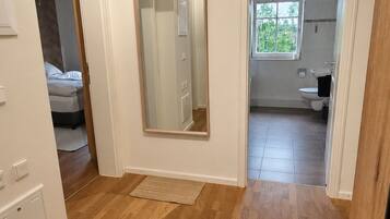 Une pièce spacieuse avec un plancher en bois, un grand miroir et une vue sur une chambre et une salle de bain.