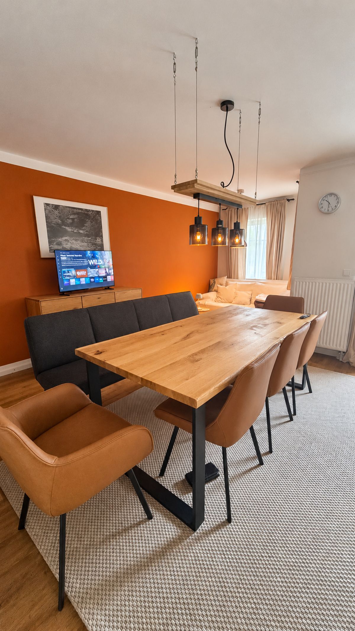 Ein stilvoller Essbereich mit einem Holztisch, Ledersesseln und Pendelleuchten.
