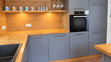 Una cocina moderna con armarios grises, encimeras de madera y un horno empotrado.