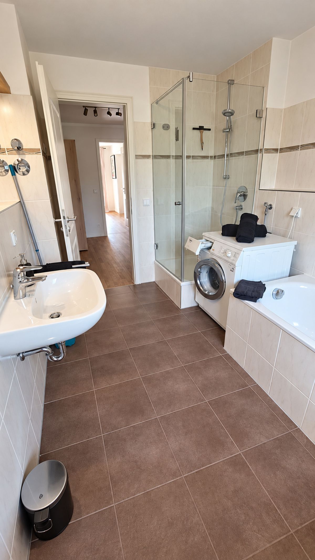 Une salle de bain moderne avec une douche à parois de verre, un lavabo, un lave-linge et une baignoire.