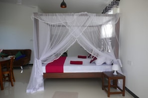 A bedroom with a four-poster bed, a bedside table, and a chair. - Denzil House: Accommodation for 3 People (Ahangama)