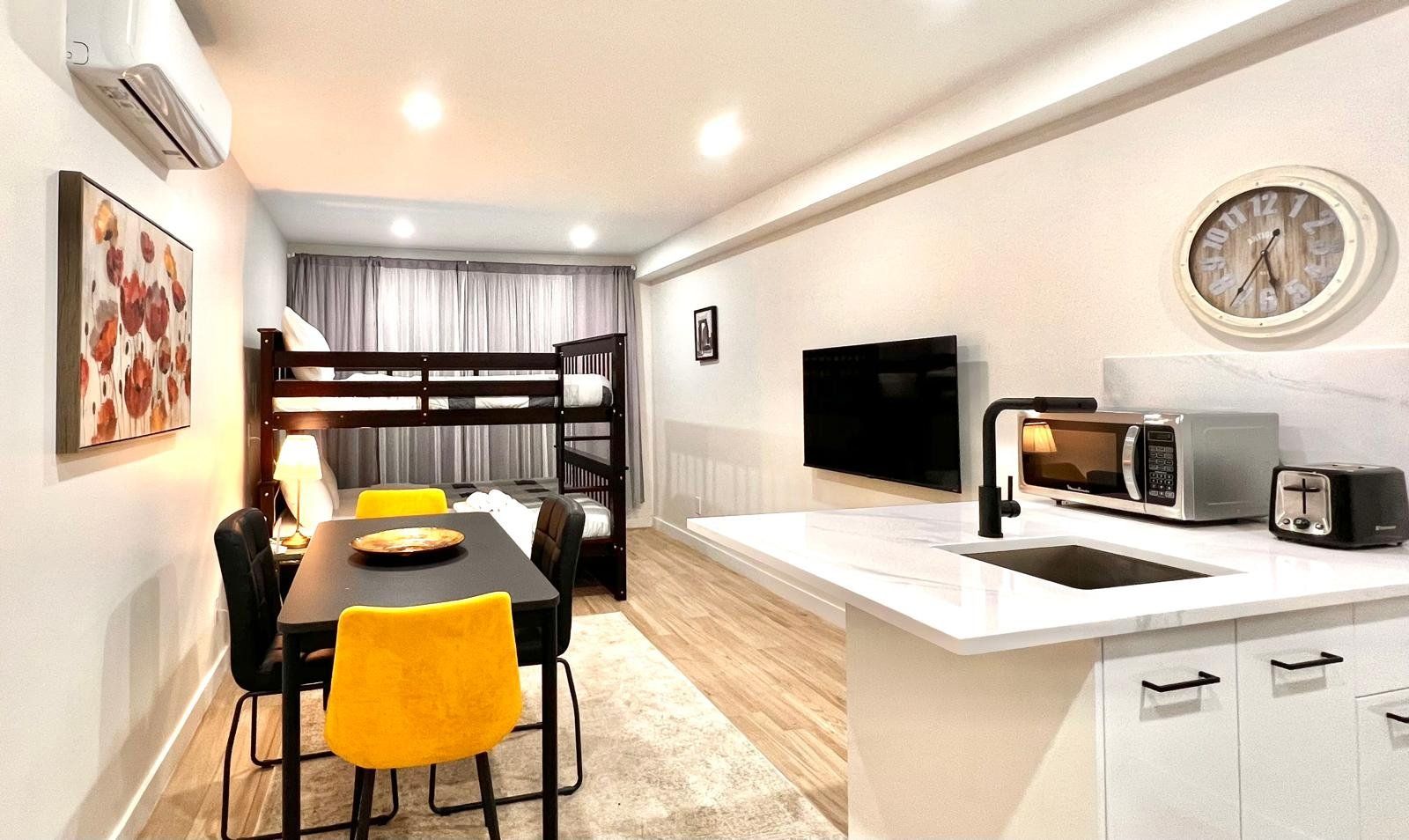 Un espacio habitable compacto con kitchenette, comedor y literas.