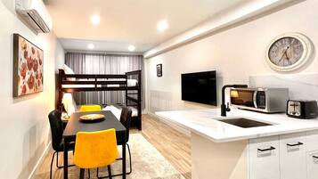 Un espacio habitable compacto con kitchenette, comedor y literas.