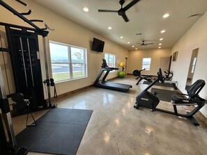Ein Fitnessstudio mit Trainingsgeräten, Laufband und einer Gewichtshalterung.