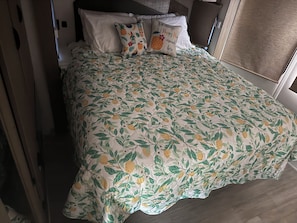 Ein Bett mit blumigem Überwurf, Kissen und einem Kopfteil.