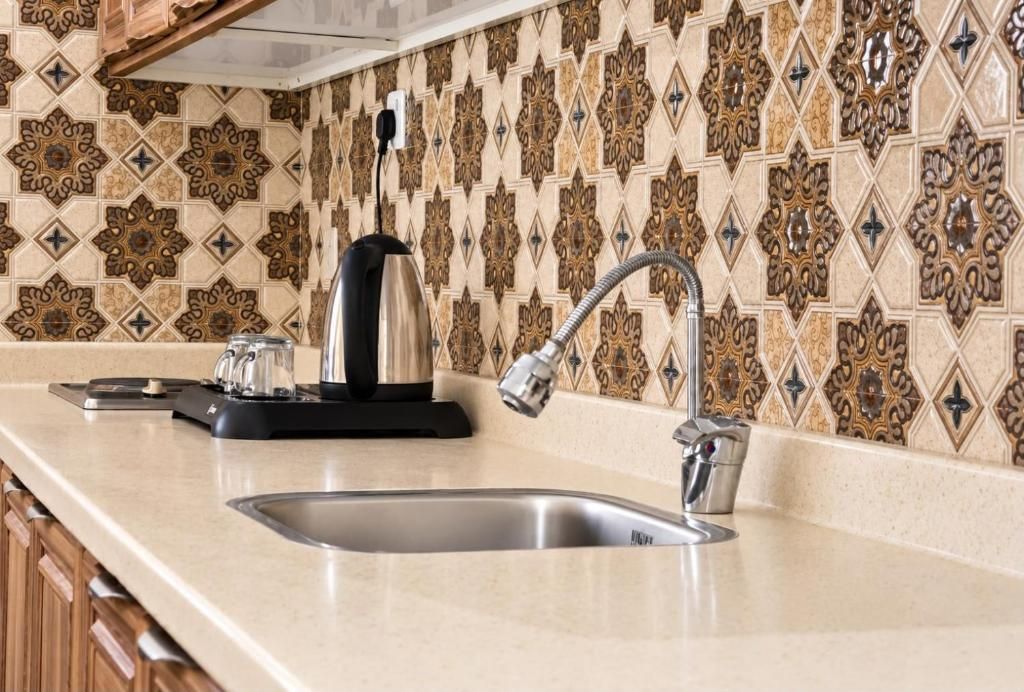 A kitchen with a stainless steel sink, a kettle, and a coffee maker on the counter.