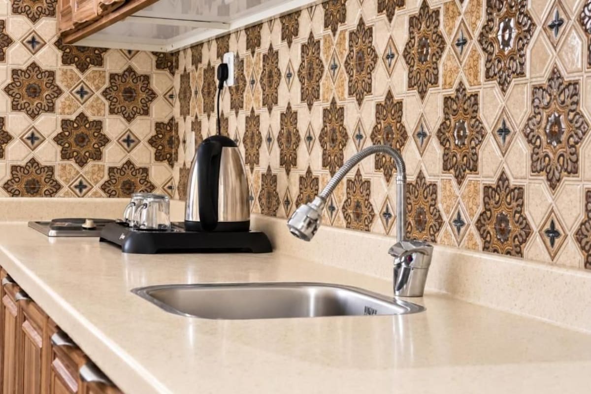 A kitchen with a stainless steel sink, a kettle, and a coffee maker on the counter.