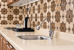 A kitchen with a stainless steel sink, a kettle, and a coffee maker on the counter. - Sleep Inn for Serviced Apartment  (Mohammed bin Mahmoud Al Hamed Street)