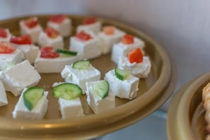 A plate of food with cubes of white cheese topped with cucumber and tomato slices. - Sleep Inn for Serviced Apartment  (Mohammed bin Mahmoud Al Hamed Street)