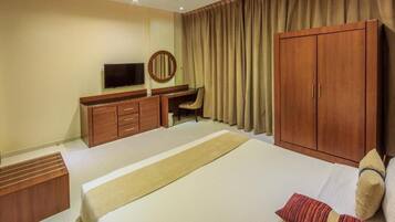 A hotel room with a bed, a desk, a television, and a wardrobe.