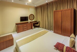 A hotel room with a bed, a desk, a television, and a wardrobe. - Sleep Inn for Serviced Apartment  (Mohammed bin Mahmoud Al Hamed Street)