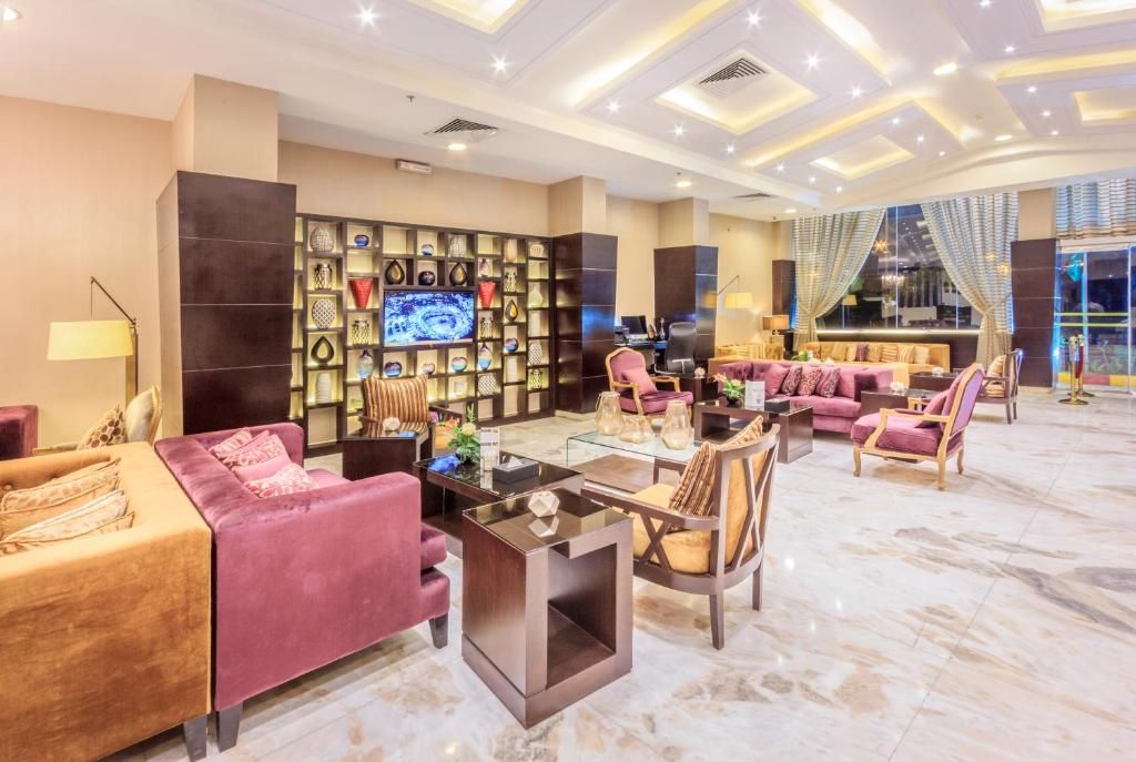 Un'ampia hall dal design moderno, con una zona salotto spaziosa dotata di divani e poltrone, un televisore a parete e una parete decorativa con diversi oggetti.