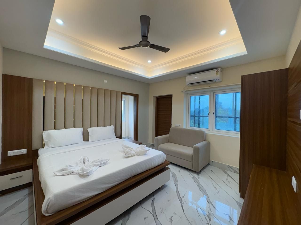 Un dormitorio moderno con cama, sofá y ventilador de techo.