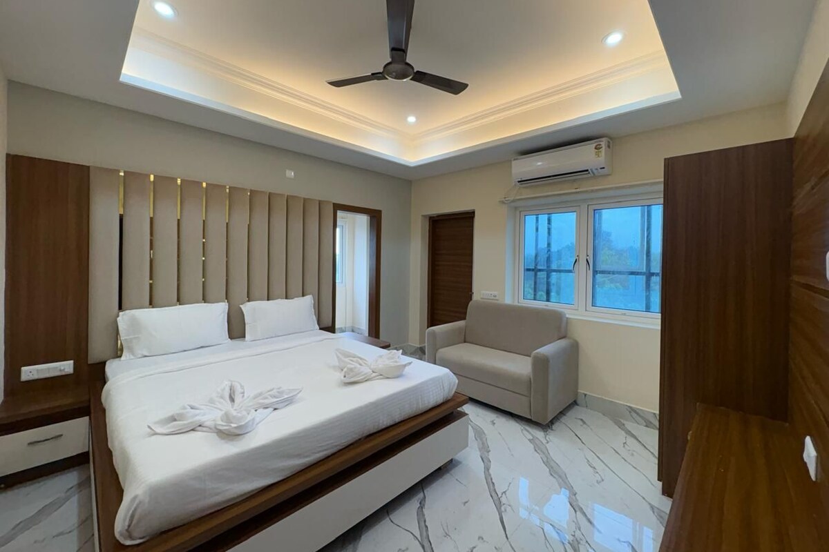 A modern bedroom with a bed, a sofa, and a ceiling fan.