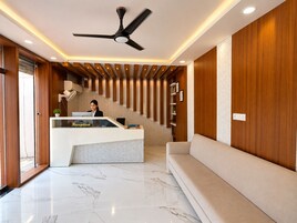 A reception area with a reception desk, a ceiling fan, a staircase, and a sofa.