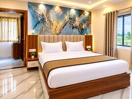 Una habitación de hotel moderna con una cama grande, piso de mármol, una obra de arte en la pared y un ventanal con cortinas.