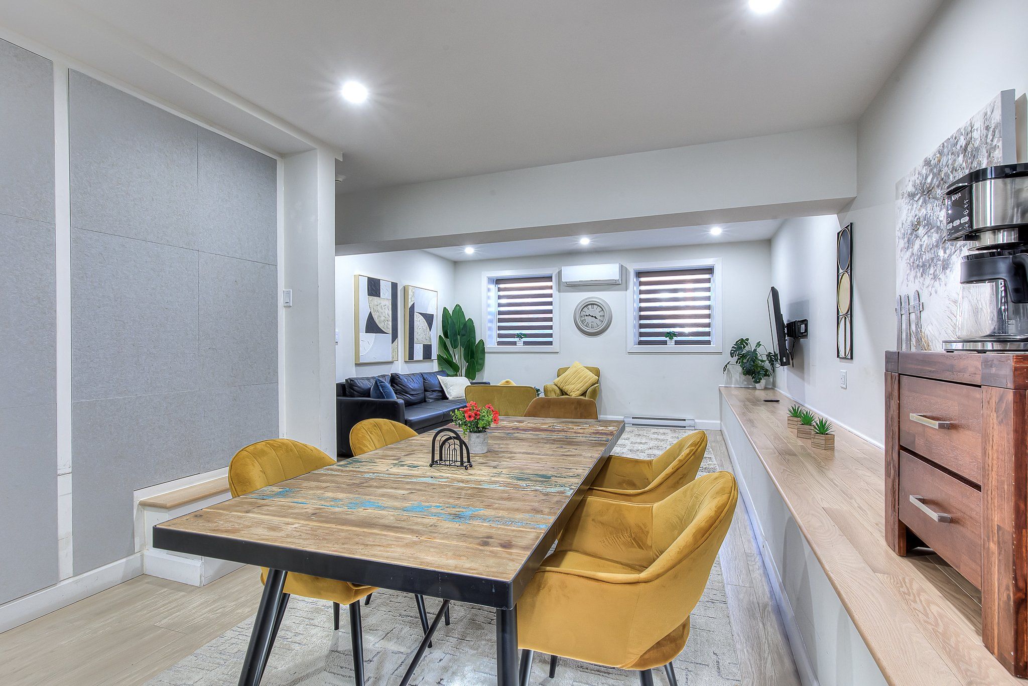 A modern kitchen with a coffee machine, wooden cabinets, and a dining area with a table and chairs.