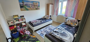 A child's bedroom with two single beds, a bookshelf, a toy car, and a painting on the wall. - Vacation Home "Im alten Kiosk" - Relaxation Right on Lake Idasee (Ostrhauderfehn)