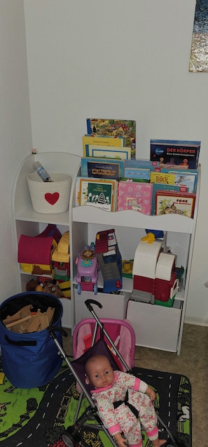A child's room with a bookshelf, a toy car, and a doll. - Vacation Home "Im alten Kiosk" - Relaxation Right on Lake Idasee (Ostrhauderfehn)