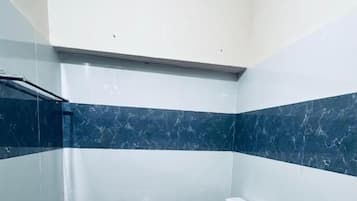 Un baño con inodoro, ducha y ventilador de techo.