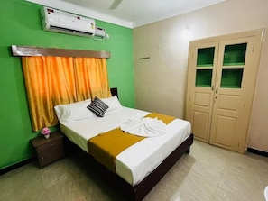 A hotel room with a bed, a nightstand, an air conditioning unit, and a wardrobe. - SKR Residency (Puducherry)