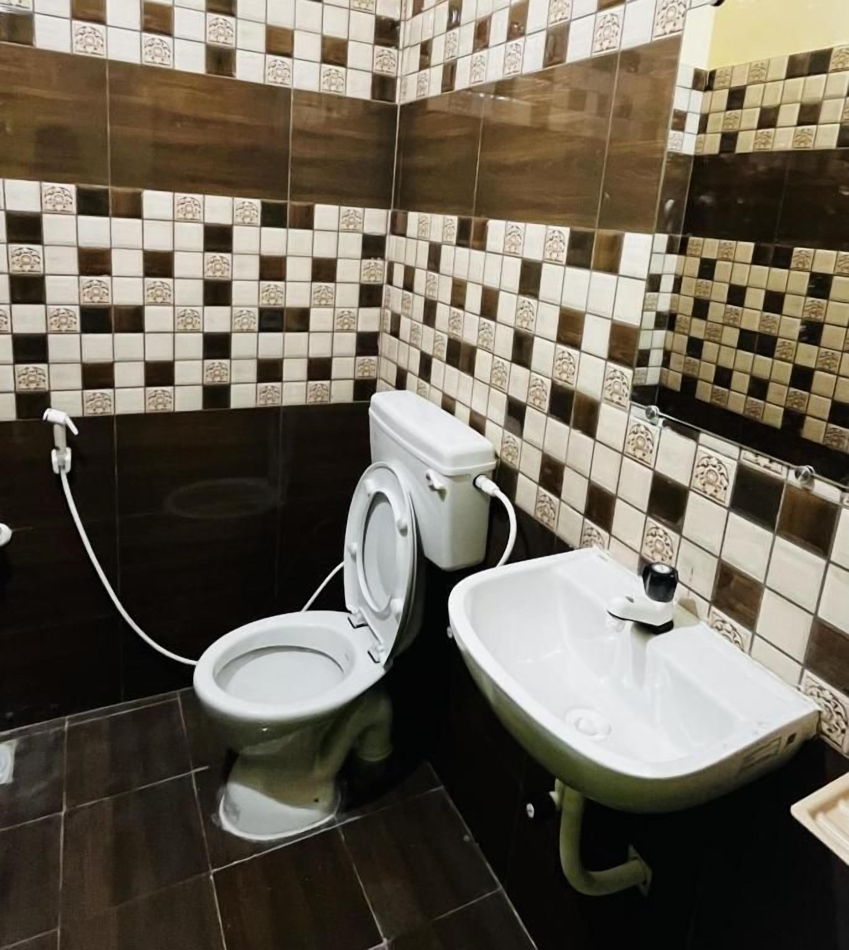 Un bagno con il water, un lavandino e pareti piastrellate.