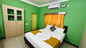 Una habitación de hotel con cama, armario, aire acondicionado y ventilador de techo.