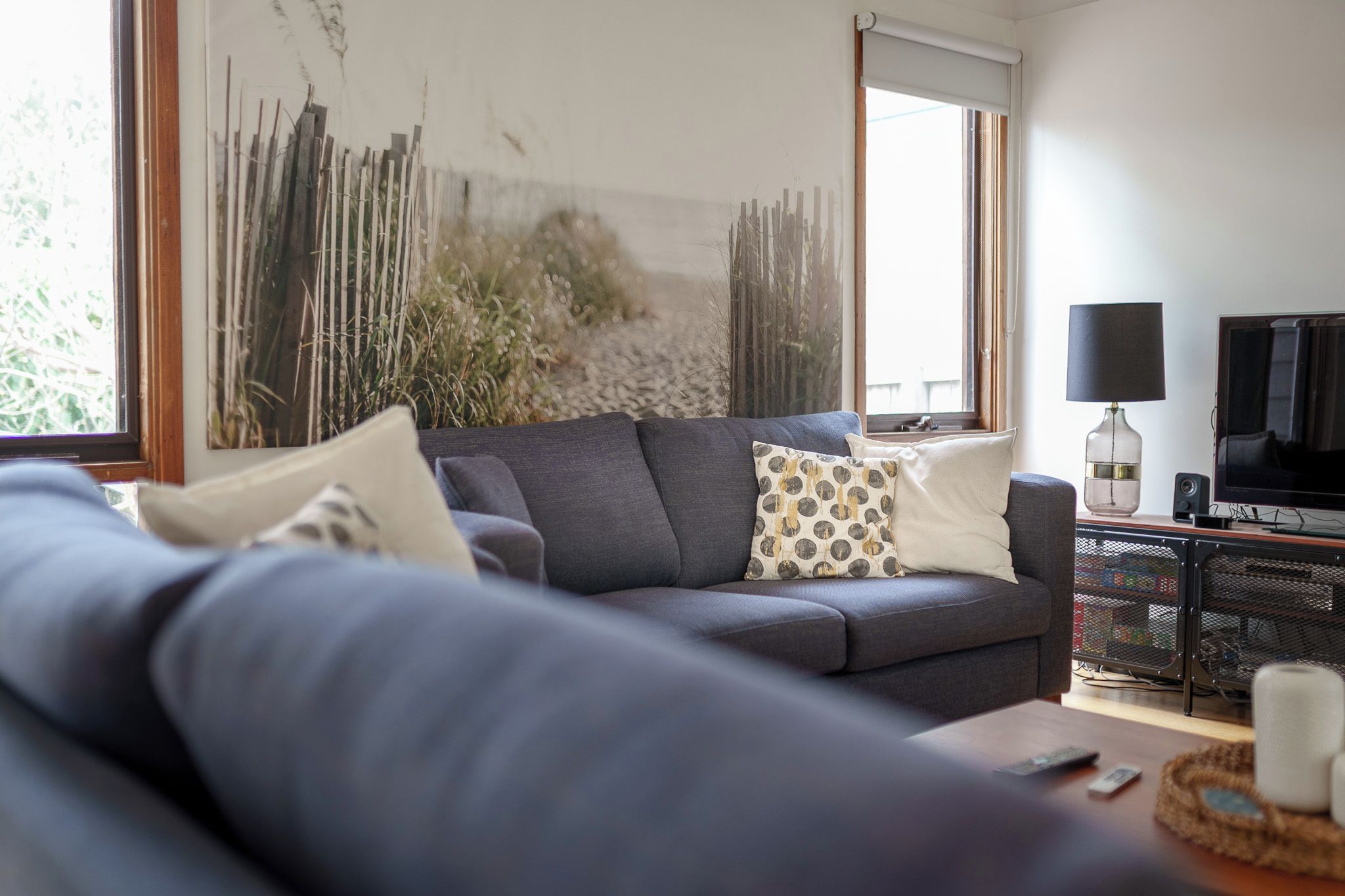 A modern living room with a grey sofa, a television, and a decorative vase.