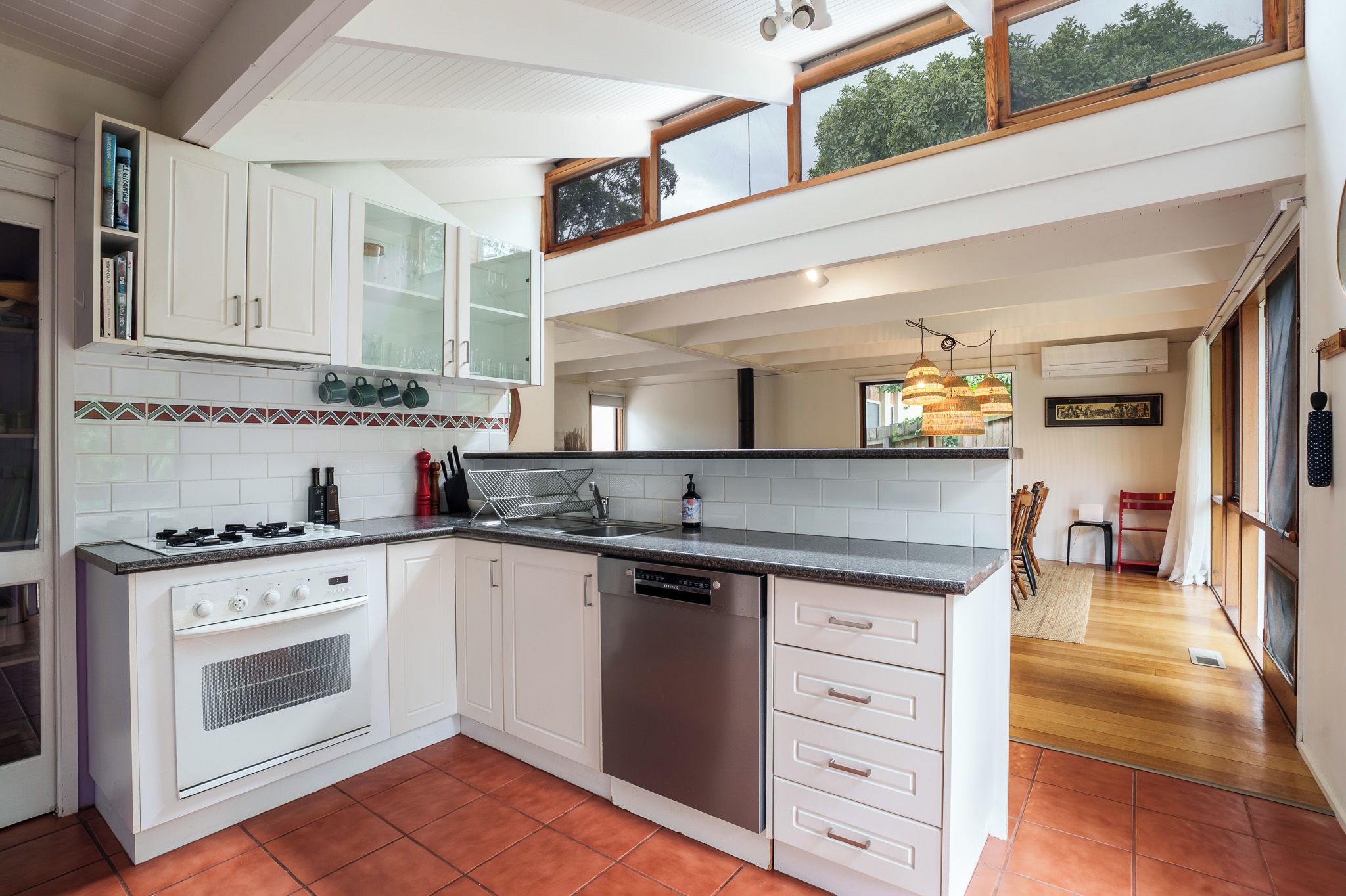 A modern kitchen with white cabinetry, a built-in oven, a dishwasher, and a granite countertop.