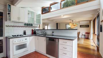 A modern kitchen with white cabinetry, a built-in oven, a dishwasher, and a granite countertop.