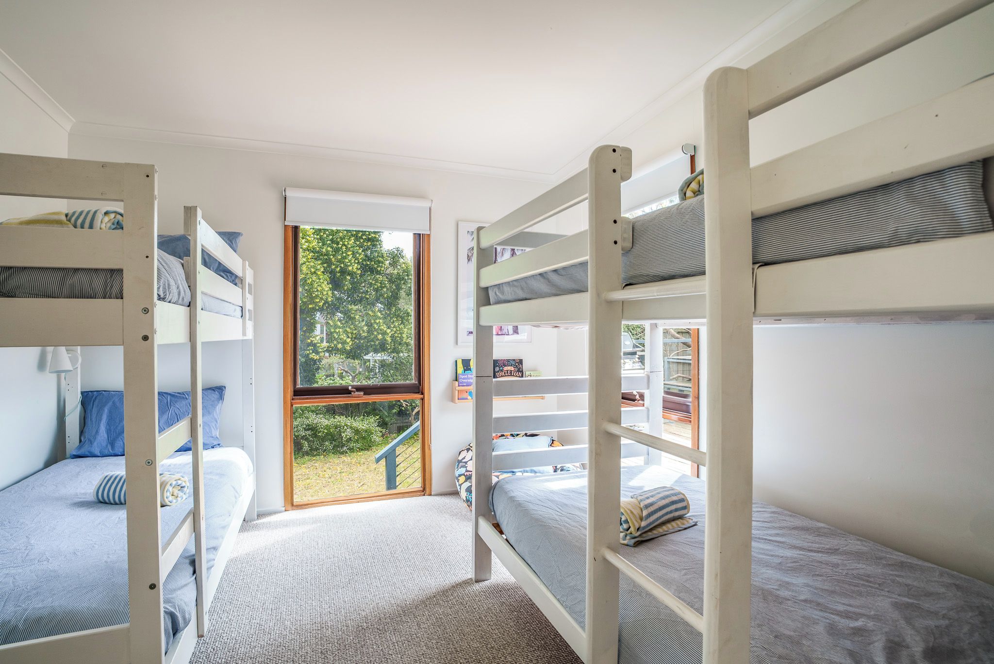 Ein Zimmer mit Etagenbetten, einem Fenster mit Blick auf Grünflächen und einer Tür zum Ausgang.