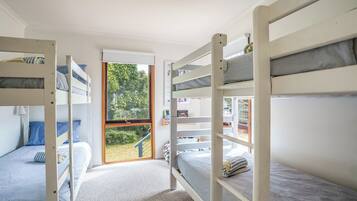 Ein Zimmer mit Etagenbetten, einem Fenster mit Blick auf Grünflächen und einer Tür zum Ausgang.