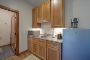 A kitchen with wooden cabinets, a microwave, a coffee maker, and a refrigerator. - Cozy Lakefront Retreat w/ Patio on the Big Chip (Hayward)