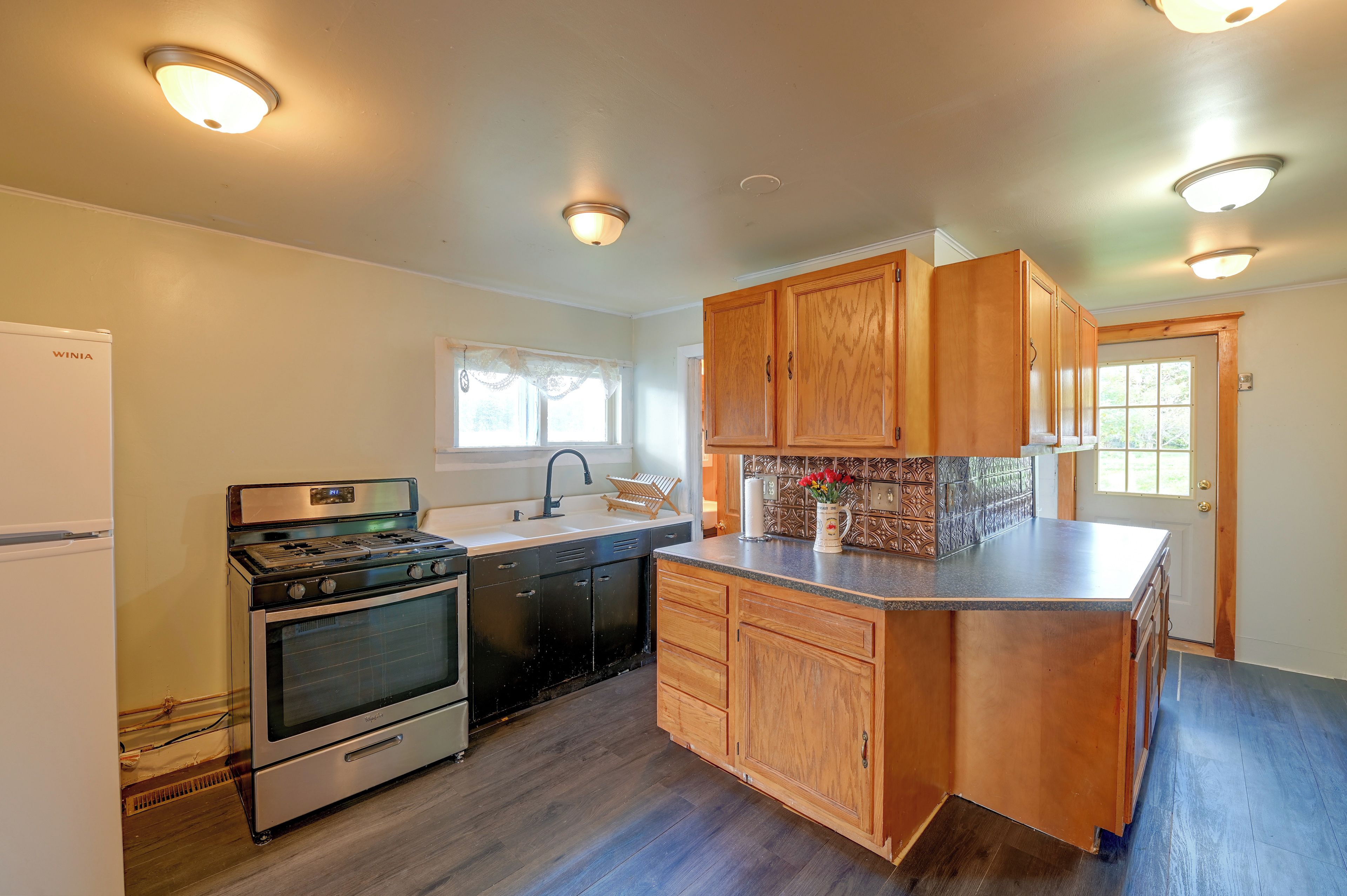 A kitchen with wooden cabinets, a built-in oven, a sink, and a window.
