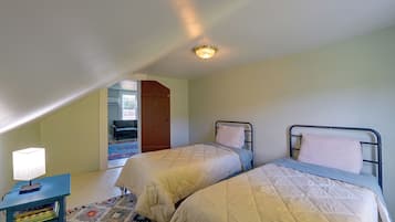 Una habitación con dos camas, un escritorio, una lámpara y una puerta que da a otra estancia.