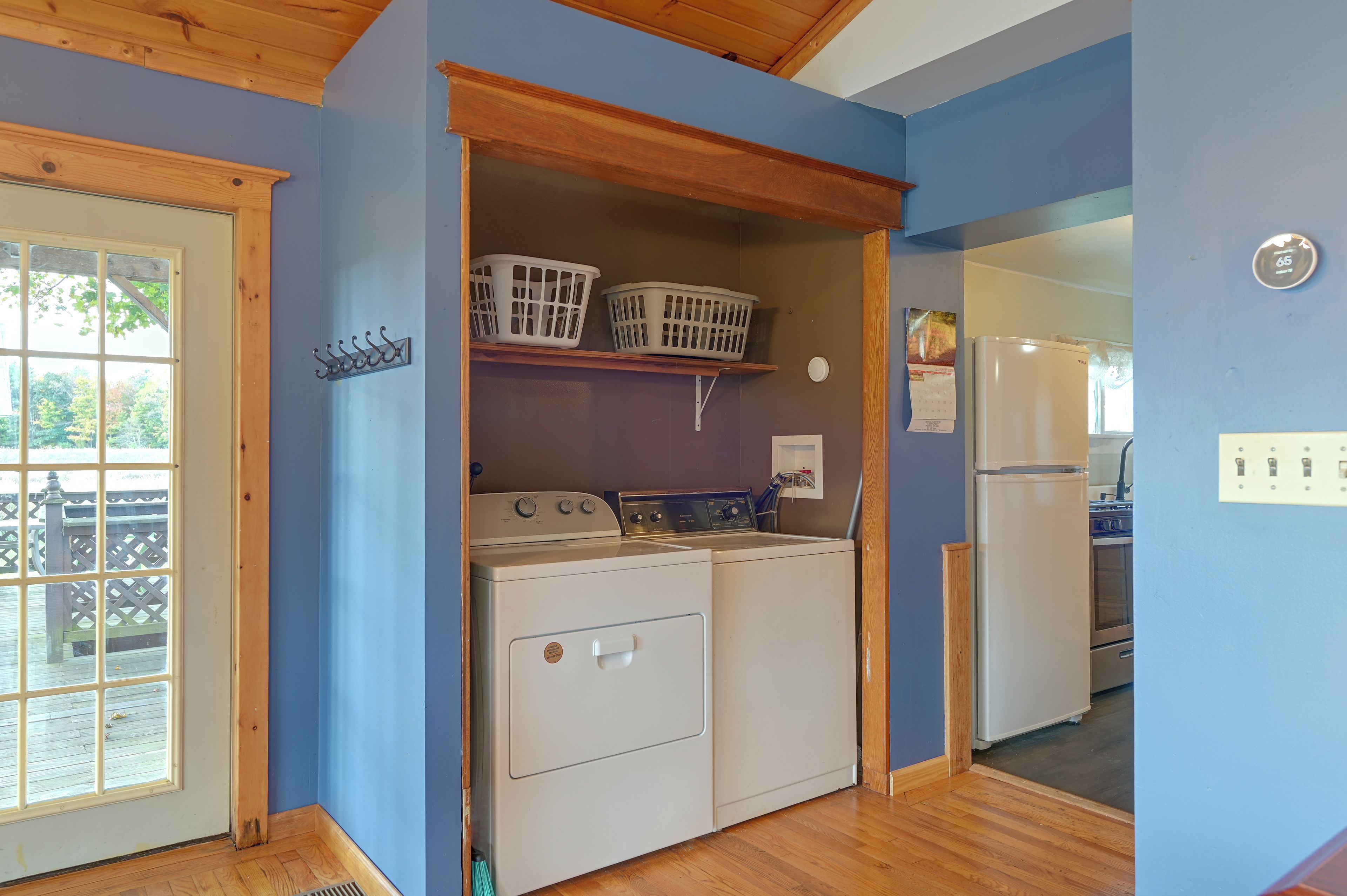 A laundry room with a washing machine, dryer, and stacked laundry baskets on a shelf.