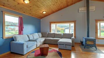 Ein gemütliches Wohnzimmer mit einem Ecksofa, Holzboden und einem Kaminofen.
