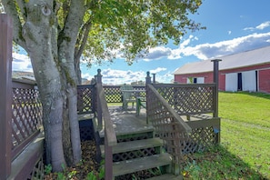 A wooden deck with a lattice fence, a bench, and a view of a red building with a metal roof.