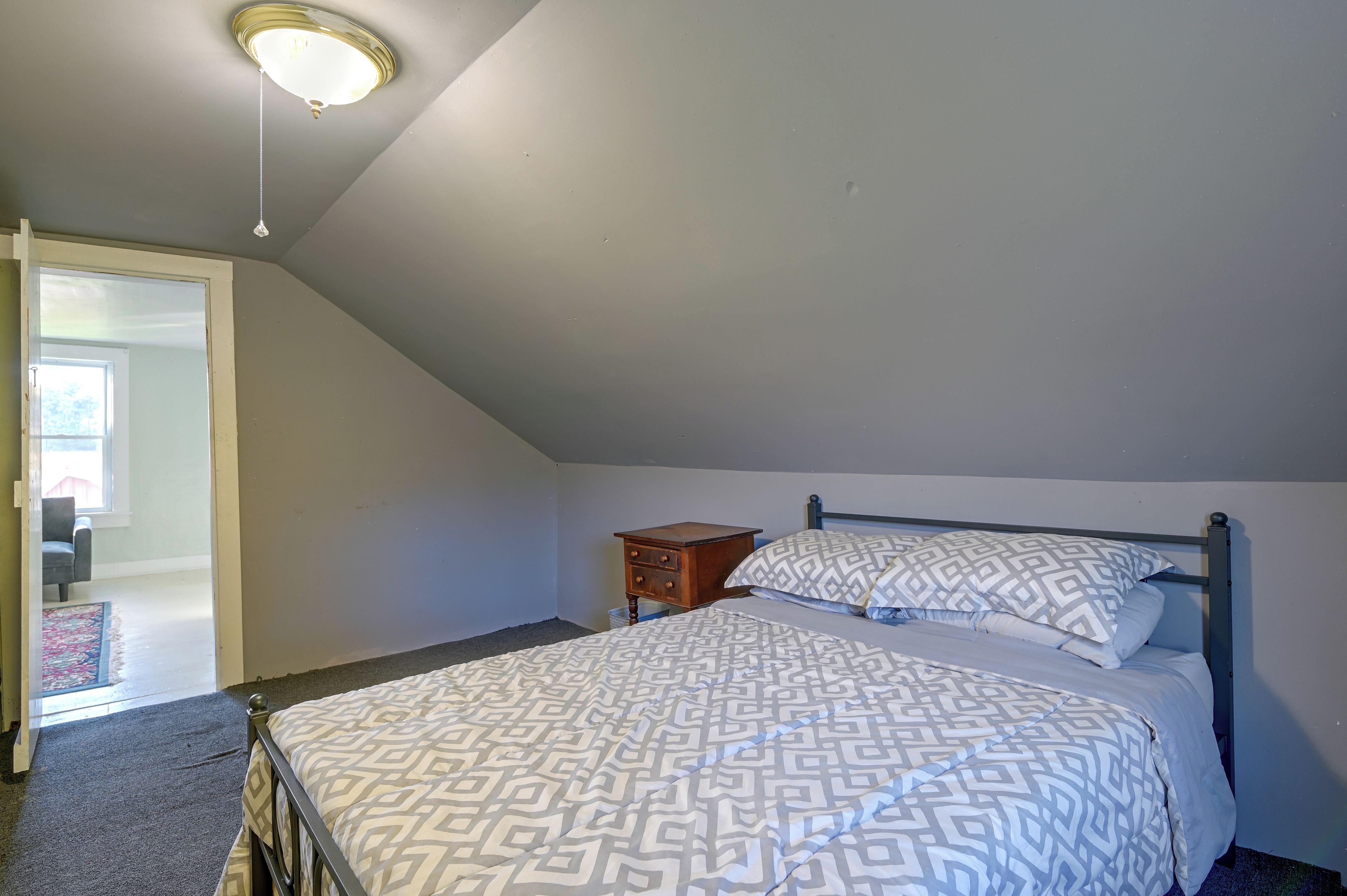 A bedroom with a bed, a nightstand, a dresser, and a ceiling light fixture.