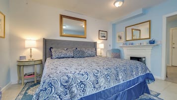 Une chambre à coucher avec un lit, des tables de chevet, une cheminée et un miroir.