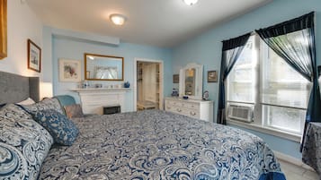A bedroom with a large bed, dresser, and a window with curtains.
