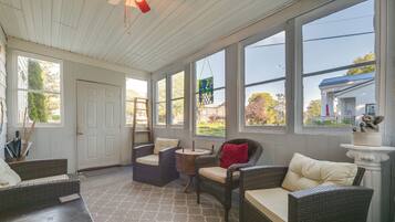 A sunroom with wicker furniture, large windows, and a view of the neighborhood.