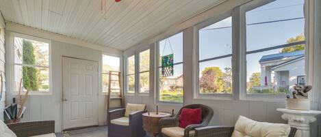 A sunroom with wicker furniture, large windows, and a view of the neighborhood.
