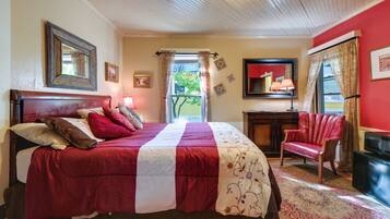 A bedroom with a large bed, a desk, a chair, and a television.