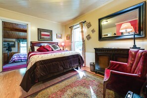 Ein Schlafzimmer mit Bett, einem Sessel, einem Spiegel und einem Kamin.