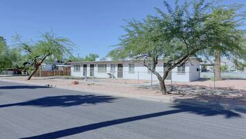 A row of single-story mobile homes with a fenced yard and sparse vegetation.