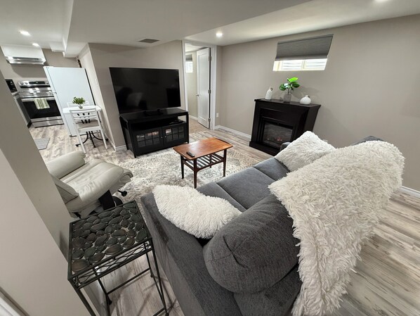 A modern living room with a grey sofa, a coffee table, a television, and a fireplace.