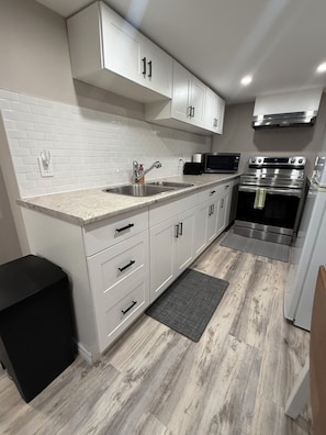 A modern kitchen with white cabinetry, stainless steel appliances, and a tiled backsplash.