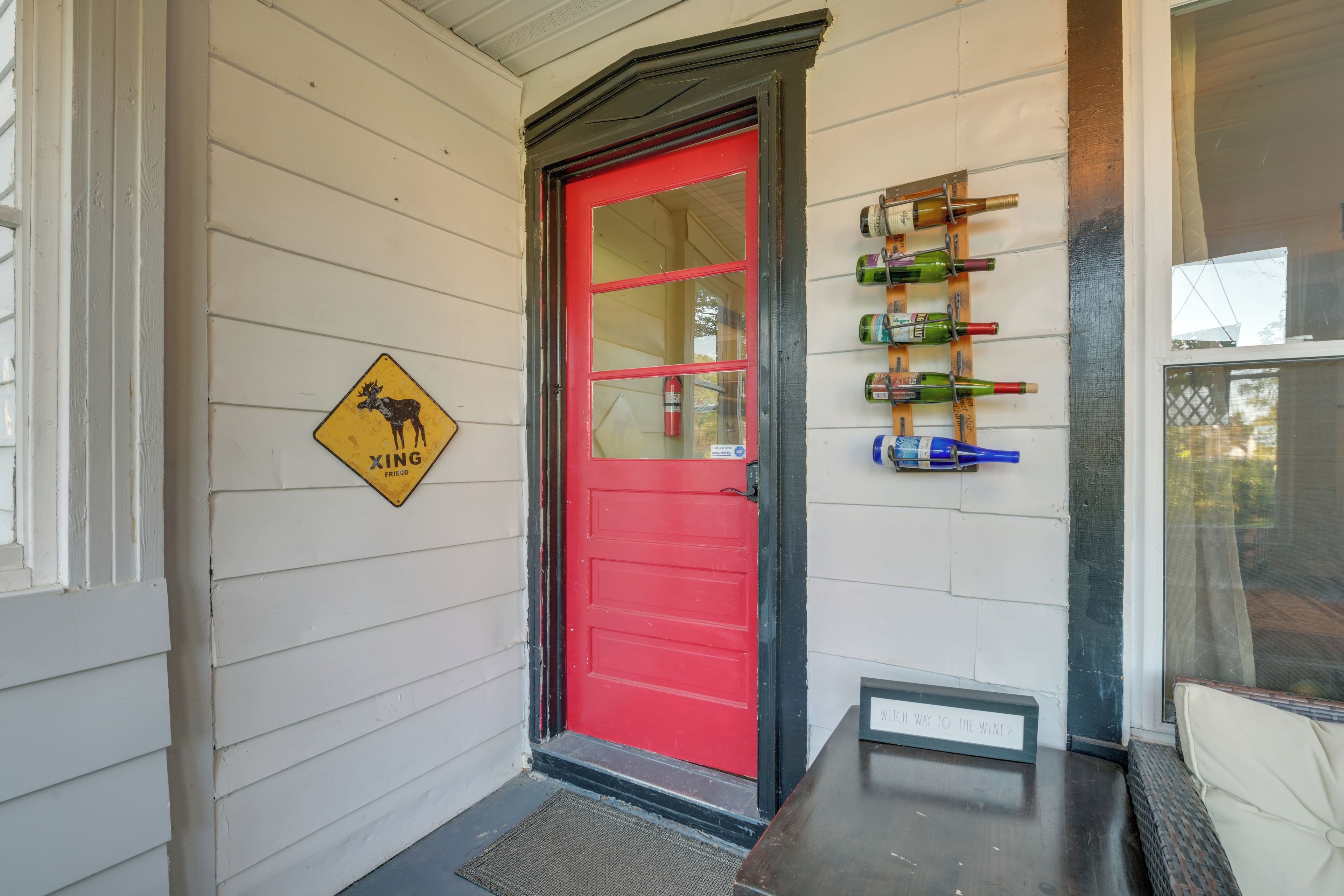 A red door with a mounted wine rack on the wall beside it.