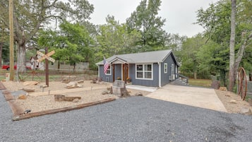 A small, single-story building with a gray exterior, a front porch, and a flagpole with an American flag.